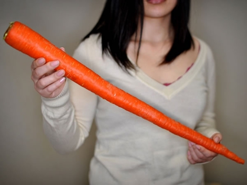Девушка держит морковку в руках